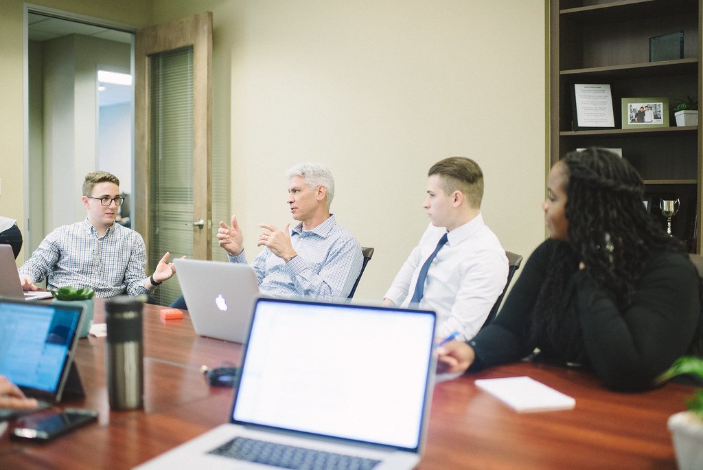 Business professionals discussing a proposal around a conference table during a commercial contracting meeting.