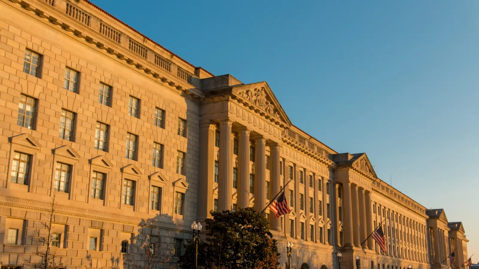 Historic federal government building with neoclassical columns and American flags, highlighting the importance of maintaining aging federal infrastructure.