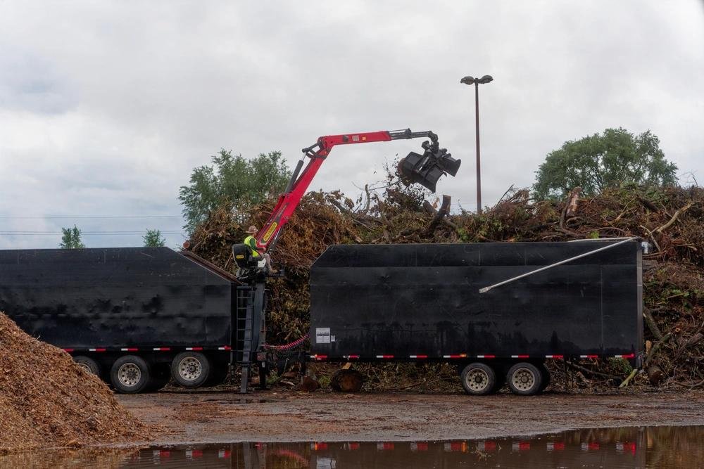 Heavy equipment loads storm debris at a FEMA-directed disaster recovery staging site in Indiana.